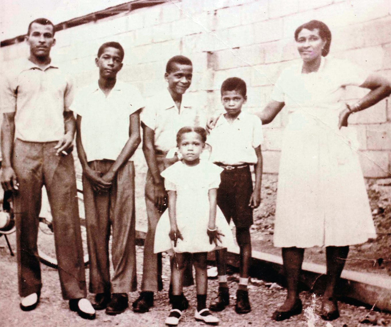 Bunny Lee (middle, smiling) with brother Don (far left, with cigarette), mother (far right), and family, 1959. Photo courtesy of Bunny Lee.